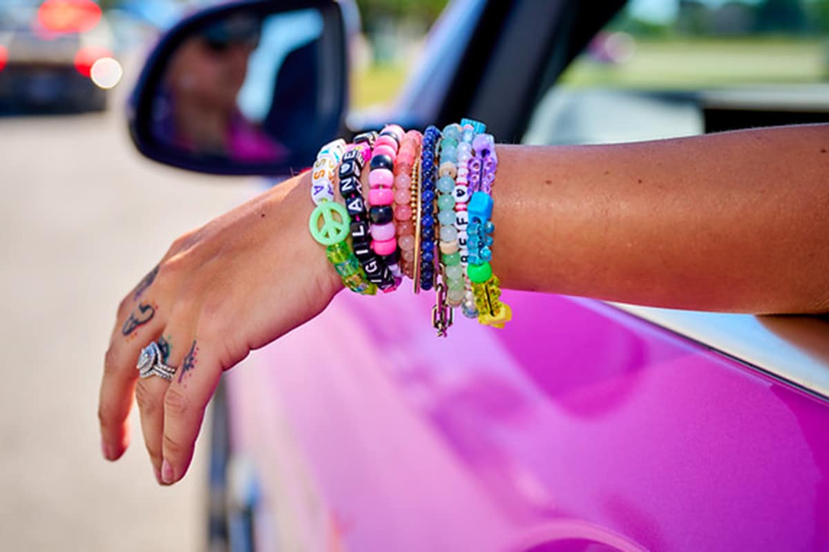 Friendship bracelets on an arm hanging out of a window